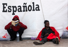 Foto: Andrés Carrasco Ragel. Tarifa (Cádiz). Dos subsaharianos en el puerto de Tarifa tras cruzar el Estrecho en patera. Uno lee la Biblia mientras el otro descansa.