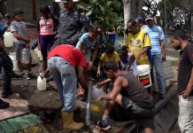 Habitantes del barrio de San Agustín, en el centro de Caracas, recogen agua de una tubería que pasa junto a la principal autopista de la capital de Venezuela, para después acarrearla a sus hogares por las empinadas escaleras que les conducen a ellas desde la avenida. La ausencia de electricidad por entre cuatro y ocho días, agravó las penurias crónicas con el recurso de amplios sectores de la población. Crédito: Humberto Márquez/IPS