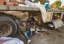 © UNICEF/Delil Souleiman: Una mujer y sus hijos se sientan debajo de un camión a medida que personas desplazadas desde Ras al Ain llegan a Tal Tamer huyendo de la violencia.