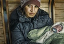 Lyuba, con su hijo de dos meses en brazos, espera sentada en una estación de tren en Uzhhorod, tras haber huir del conflicto en Ucrania. @ Unicef | Olena Hrom