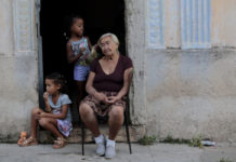 En la entrada de su vivienda, una mujer mayor cuida a dos niñas en La Habana, Cuba. © Jorge Luis Baños / IPS