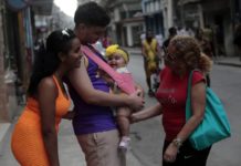 Un padre sostiene a una bebé junto a su pareja, mientras hablan con su suegra, en una calle de La Habana © Jorge Luis Baños / IPS