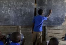 Un joven escribe la consigna «La educación no puede esperar», de la campaña del Fondo de Educación en Emergencias de las Naciones Unidas, en la pizarra de una escuela de Camerún. © Daniel Belounou/ECW