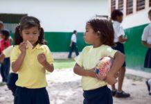 Canaima, venezuela, el 11 de noviembre de 2010: chica pemon con una bola que mira a la muchacha con la oblea en el patio de la escuela