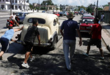 Un grupo de conductores empujan un auto al final de una extensa fila para reabastecer combustible en La Habana. © Jorge Luis Baños / IPS
