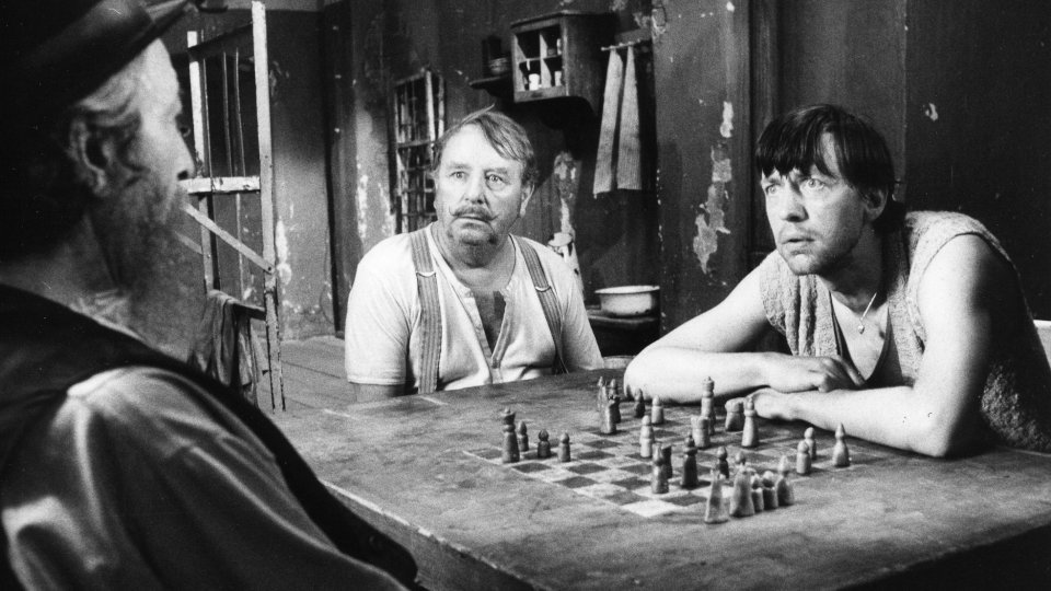 Fotograma de la película. Grünstein se vislumbra a la izquierda, Spiros en el centro y Ludeck a la derecha. Los tres en prisión ante el tablero