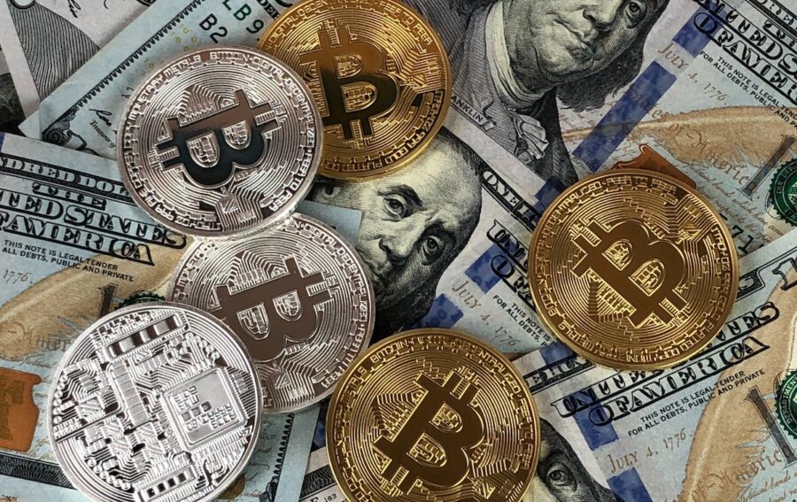 bitcoins-sobre-billetes-de-dolares-900x567 El papel vital de las criptomonedas en la evolución del dinero
