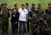Roberto Duterte hace su gesto de campaña de "puño de hierro" rodeado de soldados.