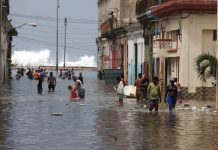Residentes de La Habana transitan por una calle vecina al malecón de la capital de Cuba, inundada por la embestida del mar tras el paso del huracán Irma. Crédito: Jorge Luis Baños/IPS