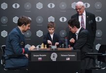 Inicio de la partida decisiva entre Karjakin y Caruana, con presencia del árbitro y un niño que pone en marcha el reloj.