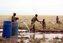 Un policía keniata da agua potable a un niño sediento en el pozo de la villa de Lotikipi.