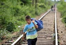 Un niño lleva sus pertenencias en un gran saco por las vías del tren que lo llevan, junto a otras pesonas, de Macedonia a Serbia. Crédito: UNICEF/Georgiev.