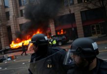 Policias antidisturbios delante de una limusina incendiada en el centro de Washington. CPJ/ Reuters/ Adrees Latif